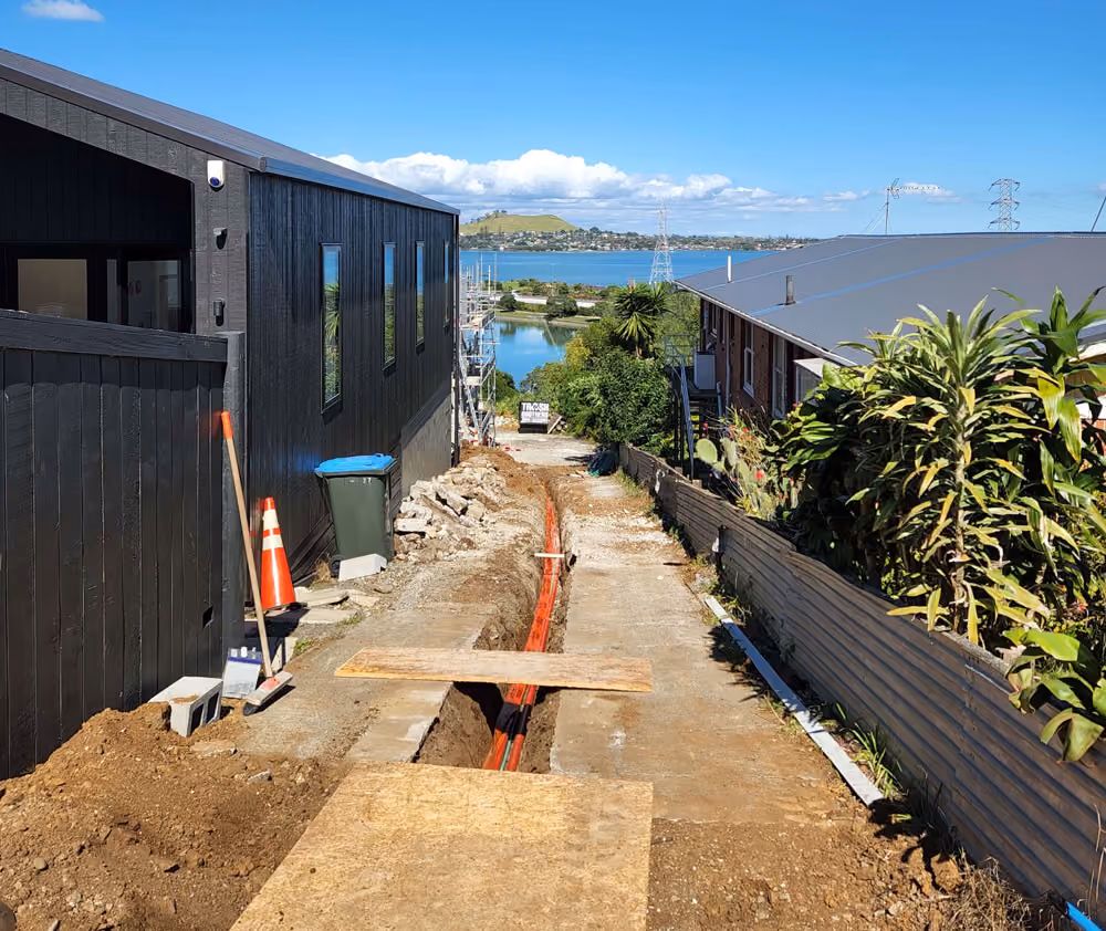 Open trench with conduit beside a new house for an outdoor power supply
