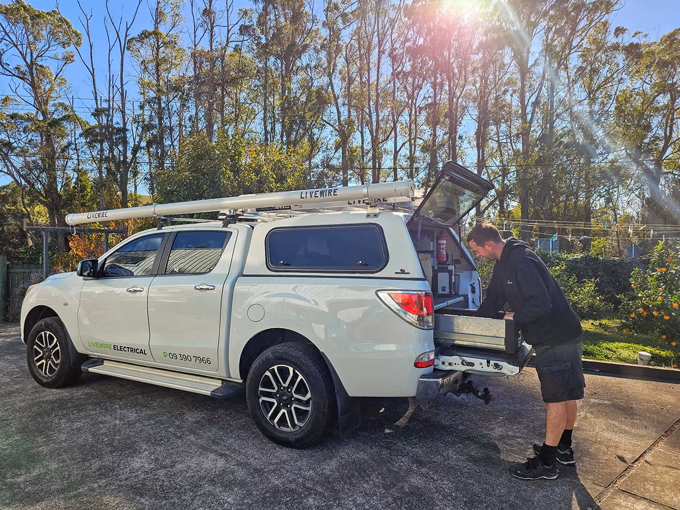 Livewire electrician unloading gear from the work ute outside a job