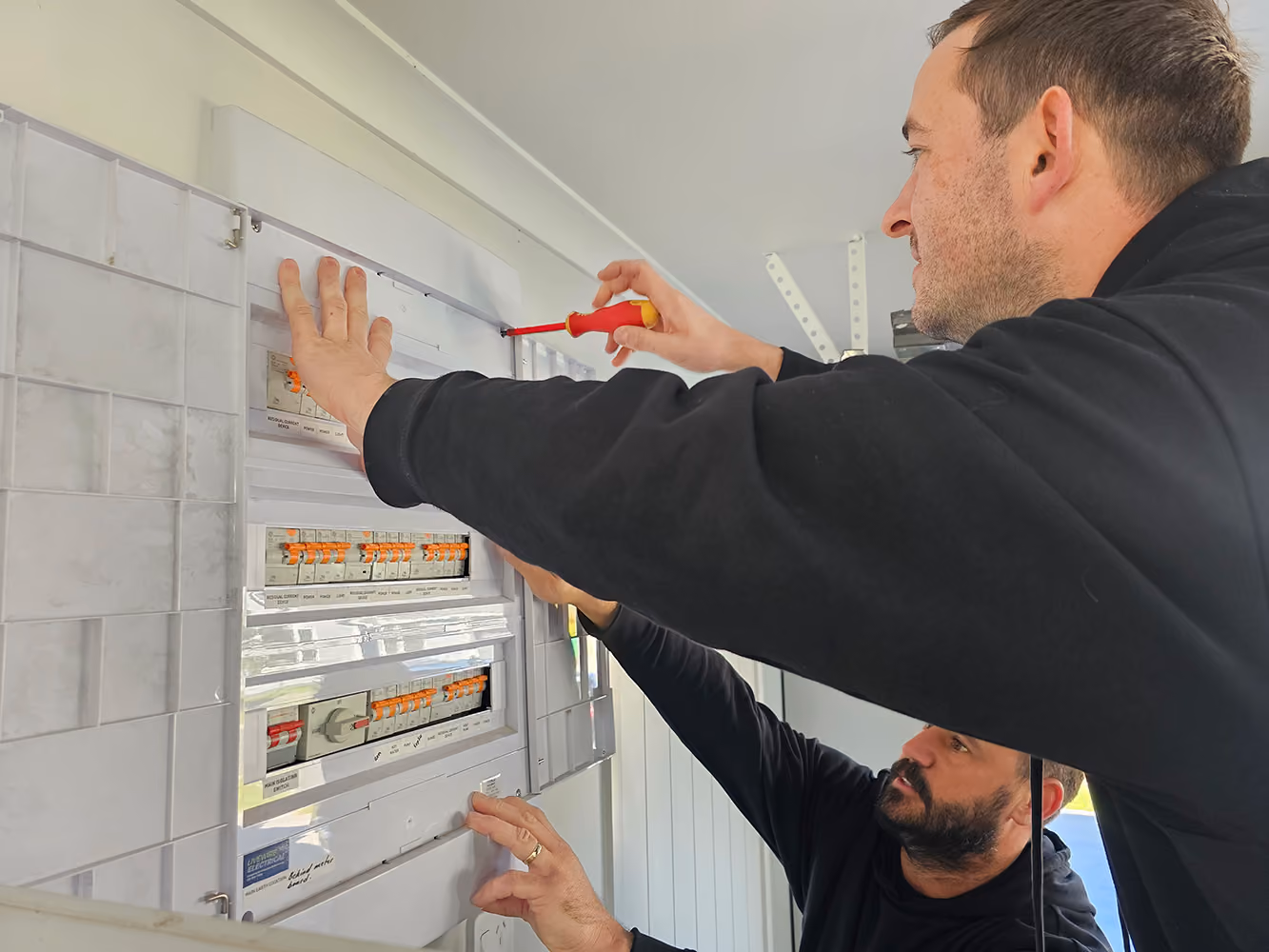 Livewire electrician working on a residential switchboard