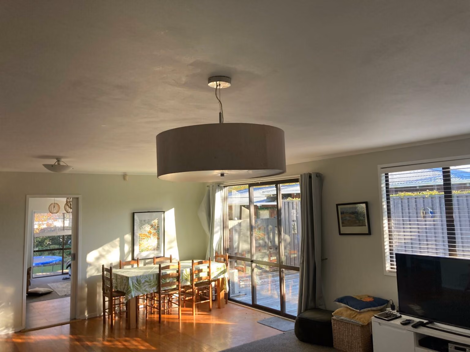 Lounge and dining room in an Auckland home with a pendant light and downlights