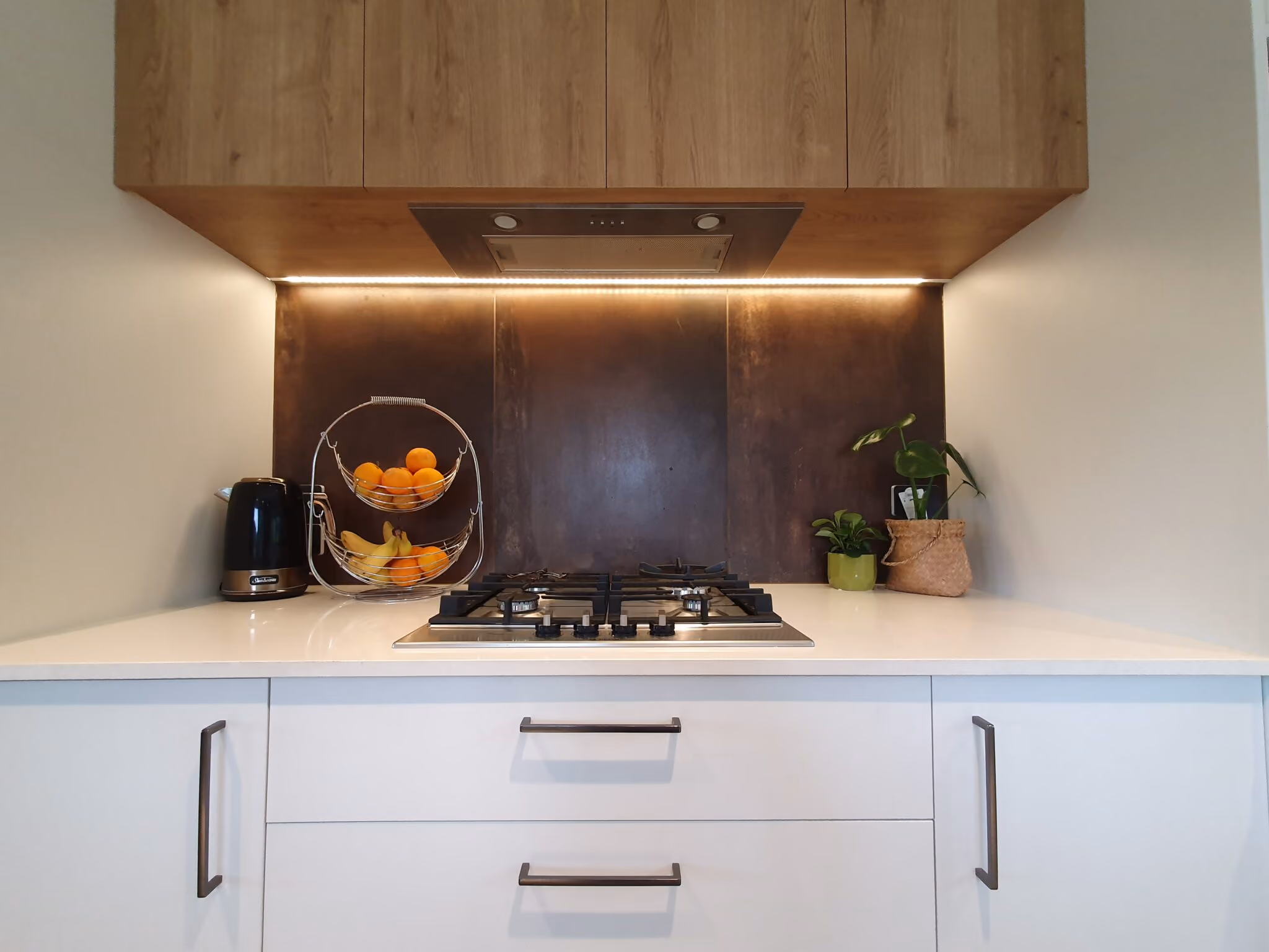 Ducted rangehood above a gas cooktop with LED strip lighting under the cabinetry