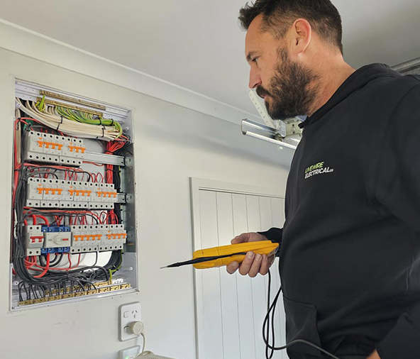 Livewire electrician testing a residential switchboard with a multimeter