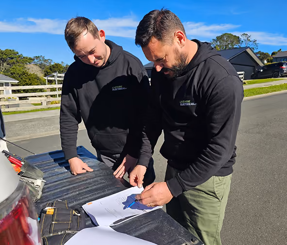 Two Livewire electricians going over job plans on the back of a ute