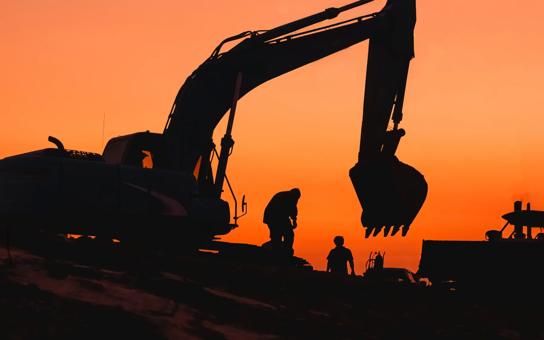 Excavator silhouetted against an orange Texas sunset