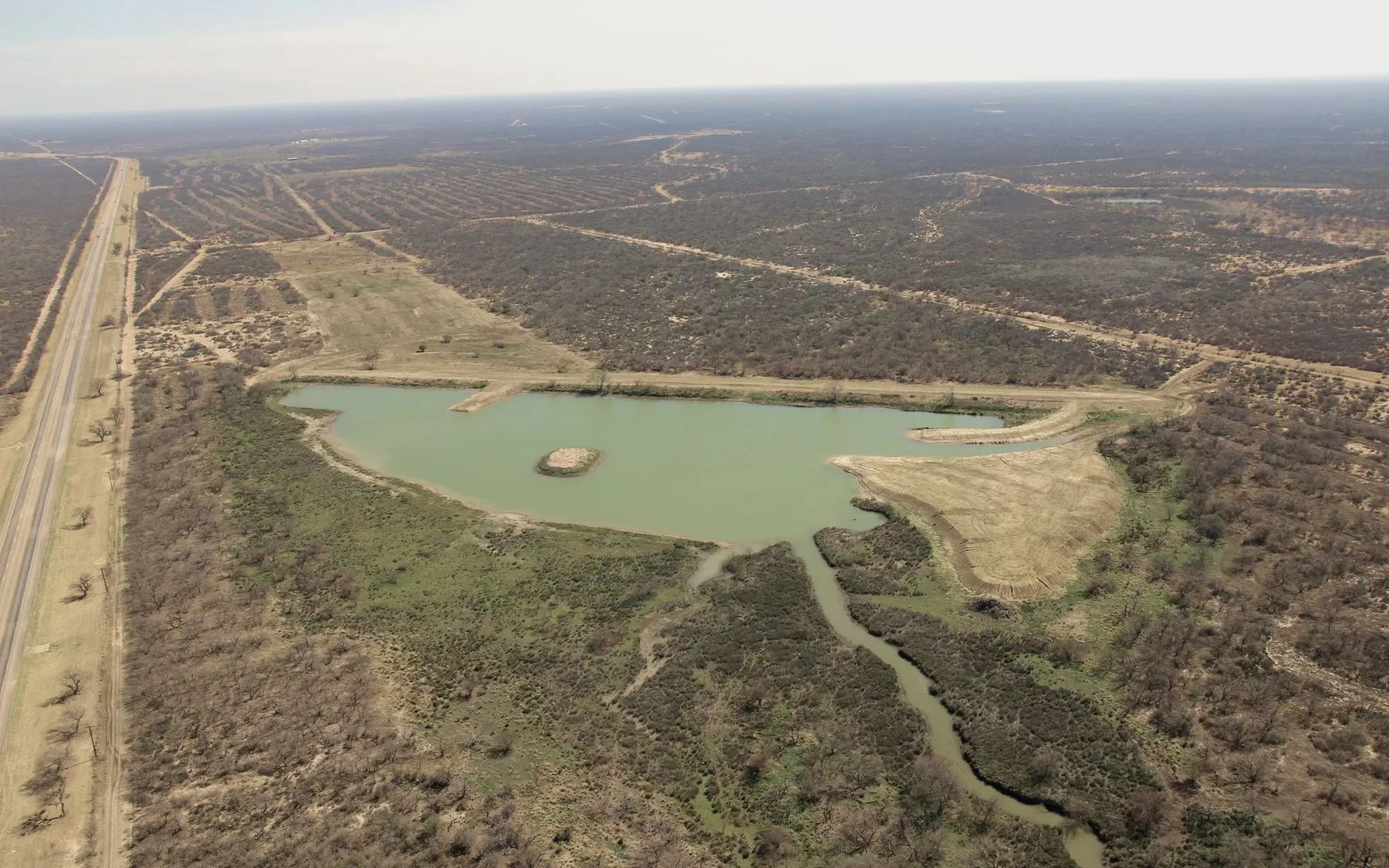 Aerial view of a ranch lake built on open Texas brushland