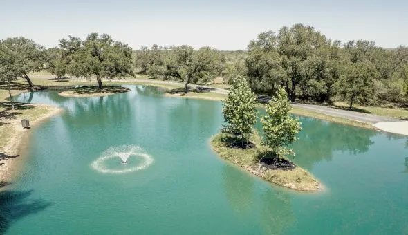 Ranch pond with an island and fountain surrounded by oak trees
