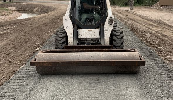 Skid steer compacting the base of a new ranch road
