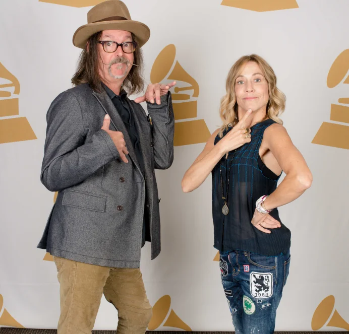 Two people posing playfully in front of a Grammy backdrop
