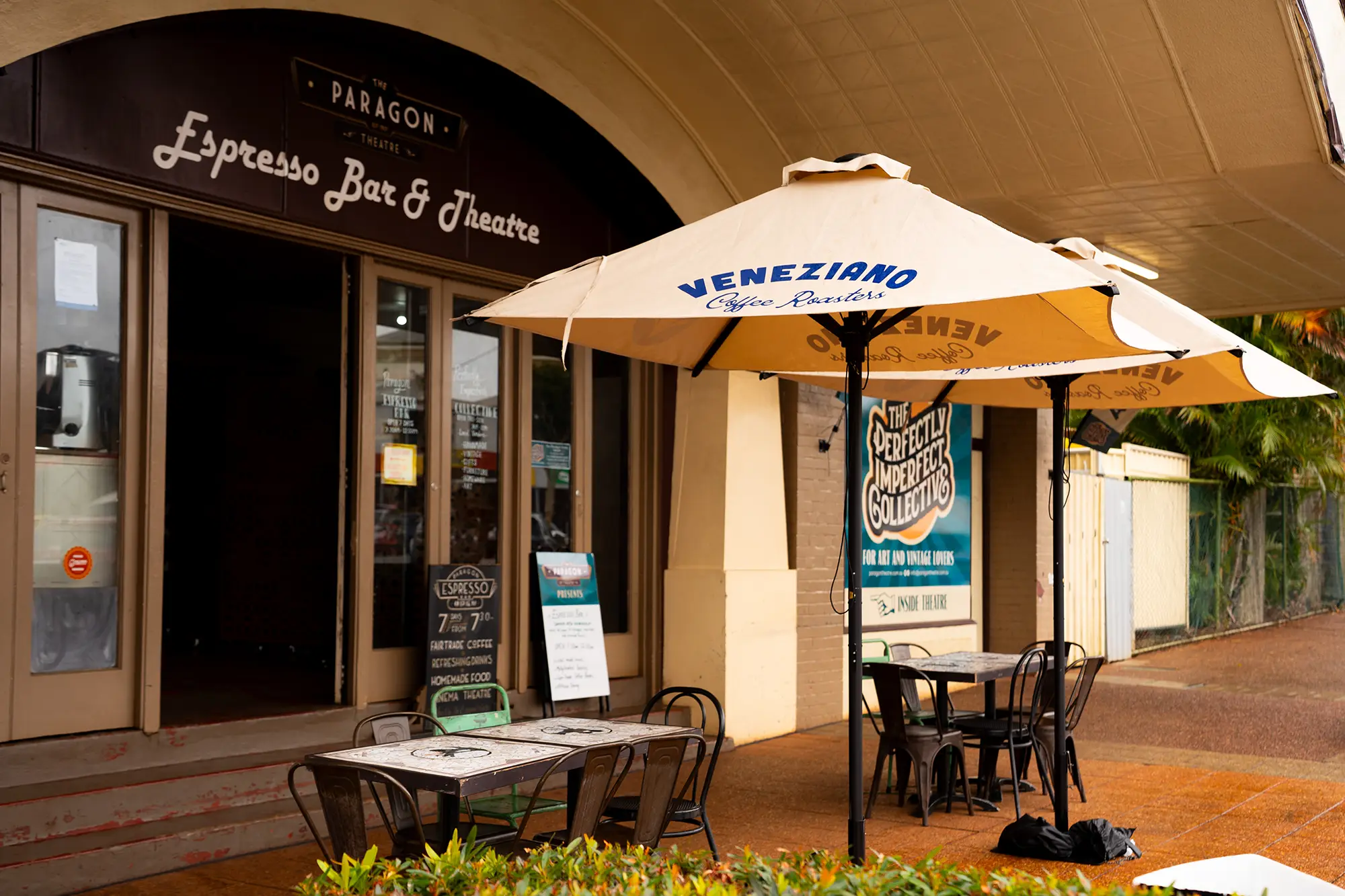 Outside of the Paragon Theatre with tables and chairs and Veneziano Coffee Roasters Umbrellas
