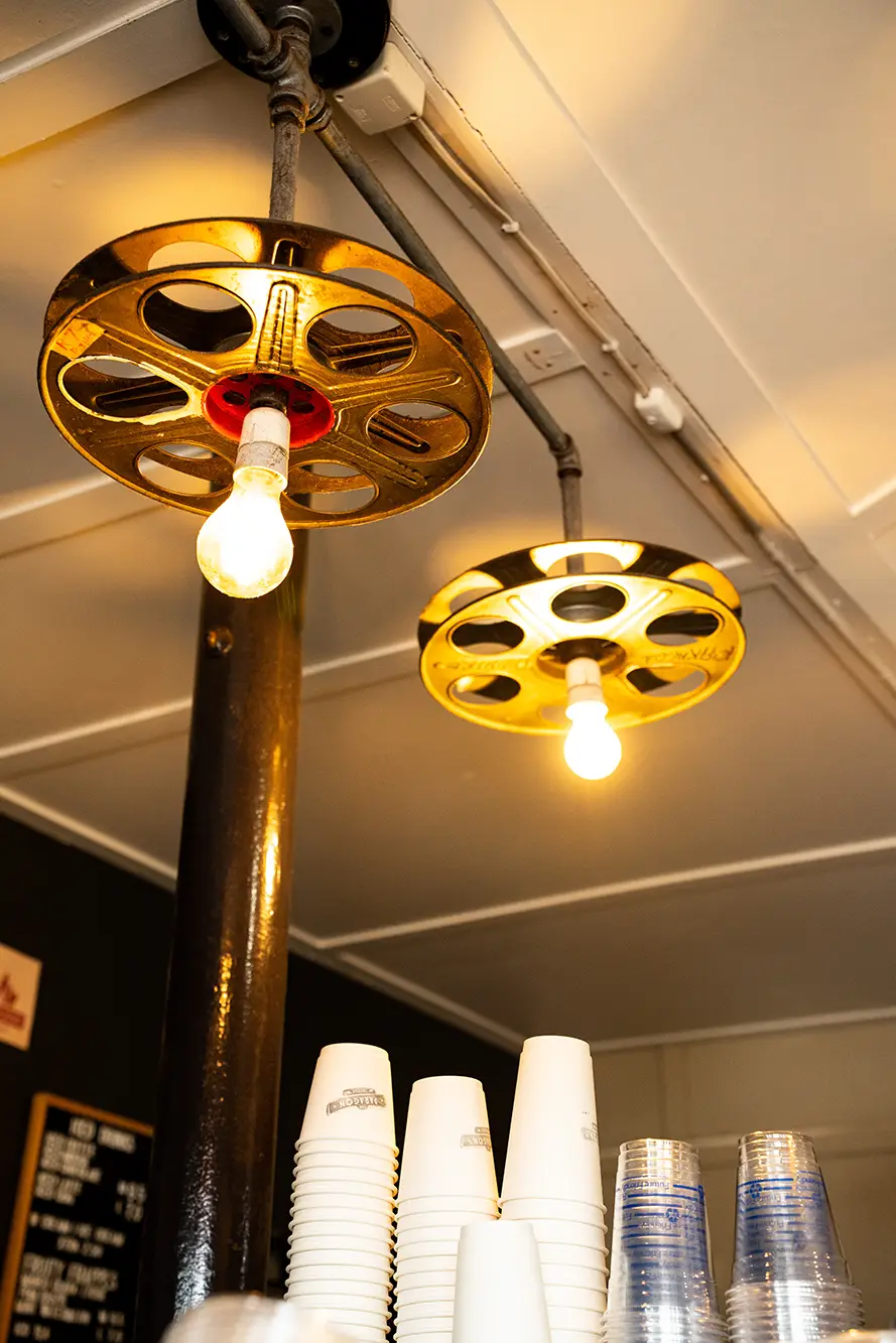 Ceiling lights made from film reels above an espresso machine