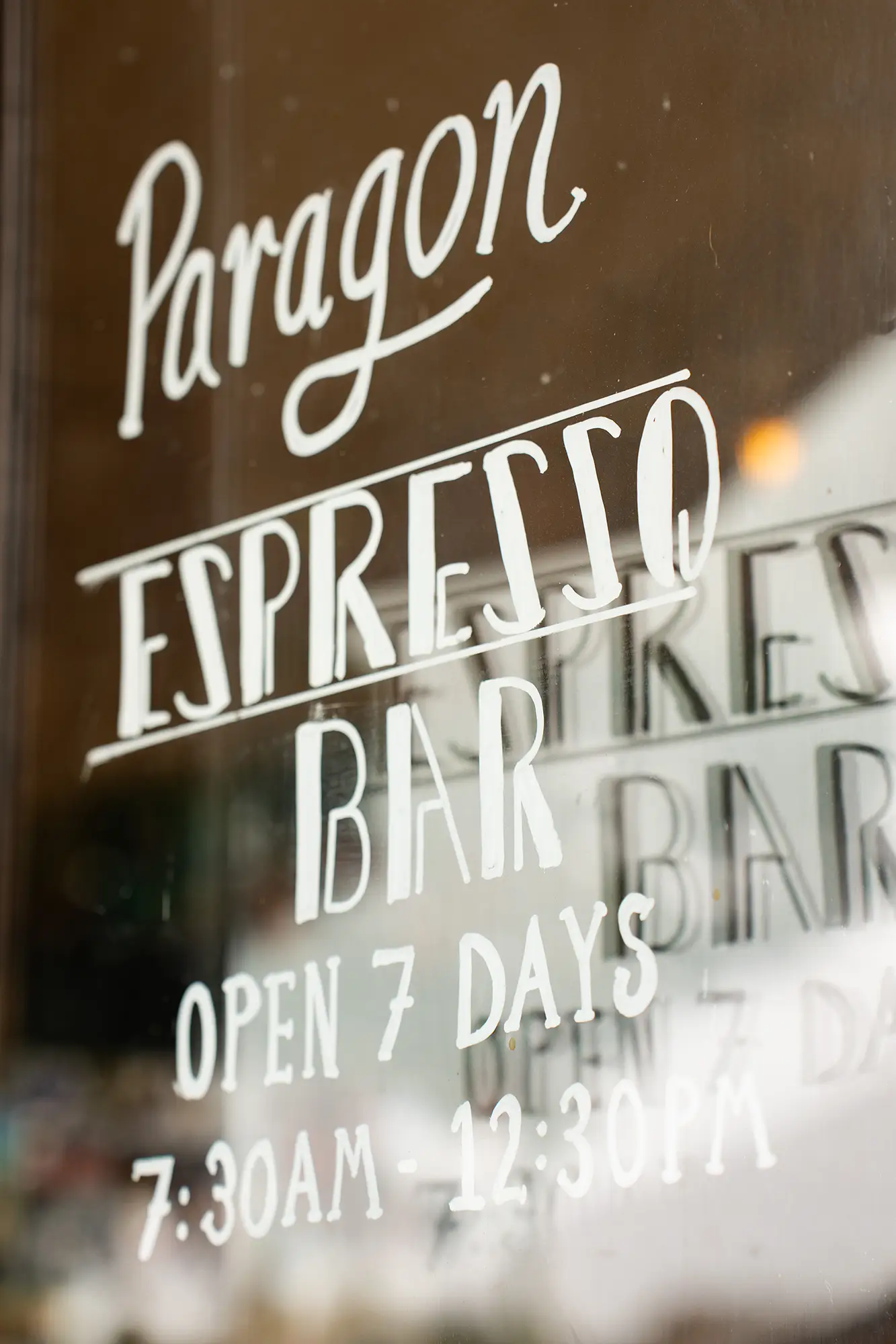 Glass pane at the front of the Espresso Bar with white chalk writing showing the opening hours