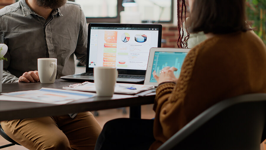 Marketing team reviewing campaign analytics dashboards on a laptop and tablet