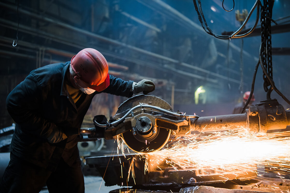 Factory worker cutting metal with sparks flying