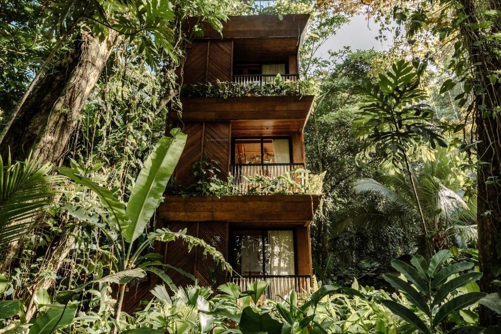 Estructura de tres pisos integrada en la densa selva con balcones en cada nivel rodeados de vegetación tropical exuberante
