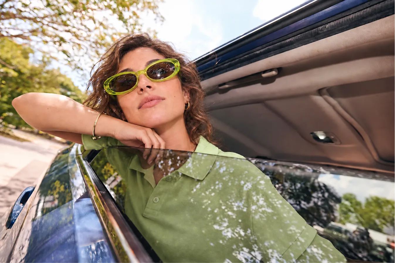 Mulher de óculos de sol encostada à janela aberta de um carro
