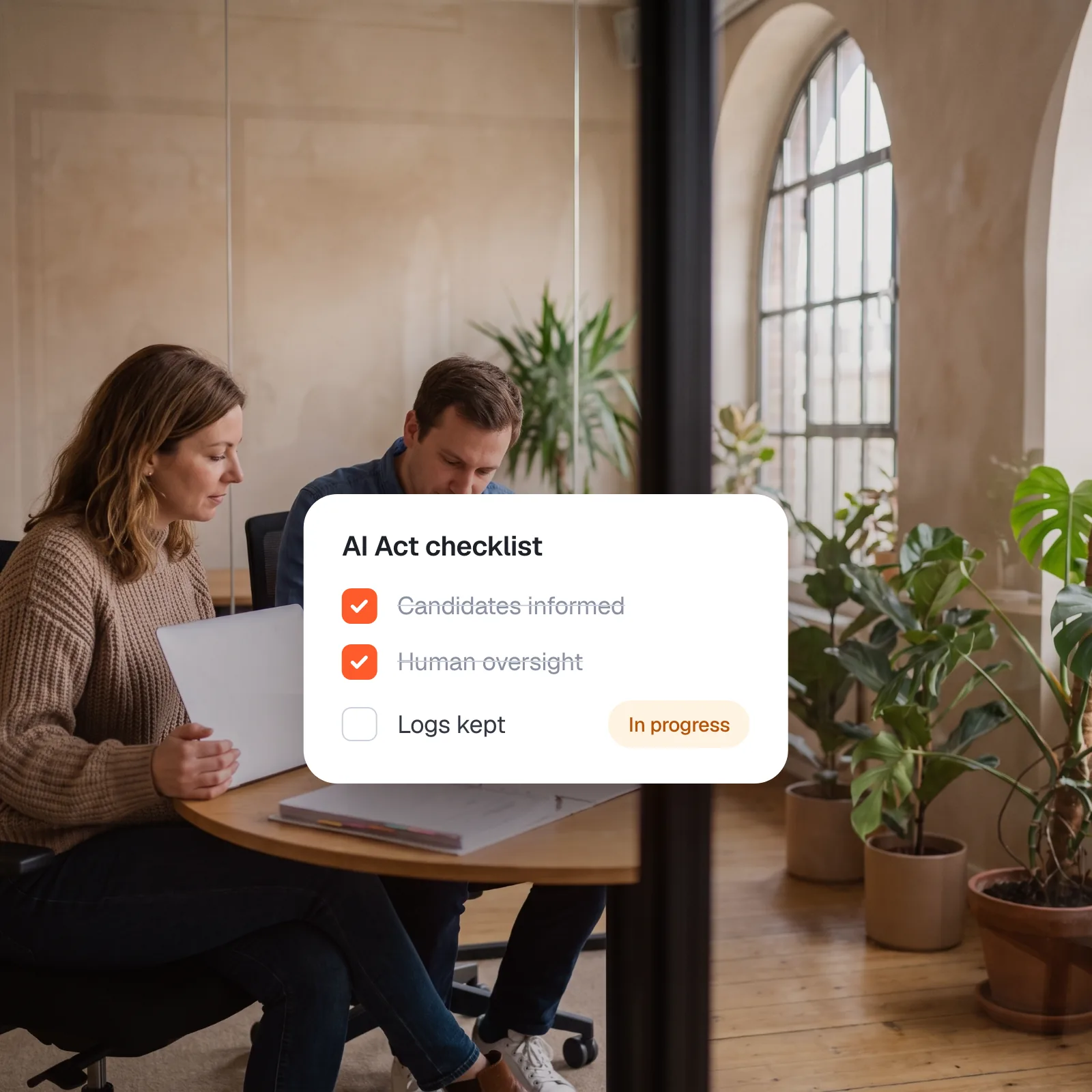 An HR lead and a colleague review a printed checklist, with an AI Act checklist: candidates informed and human oversight done, logs kept in progress