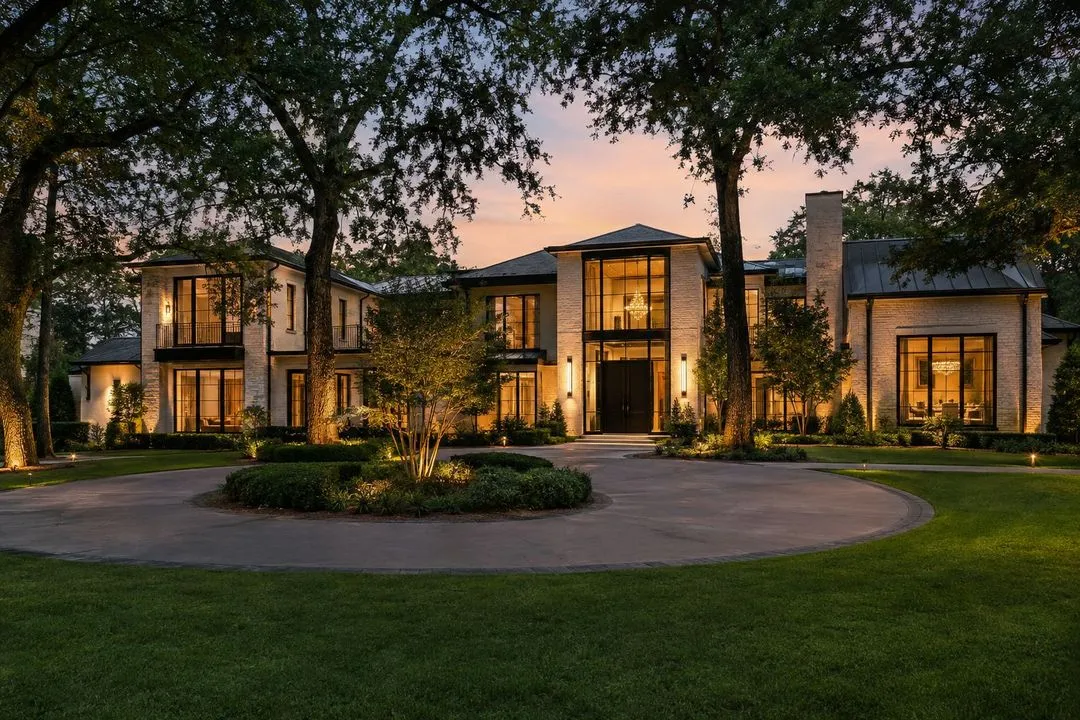 A stone house with a circular drive at dusk