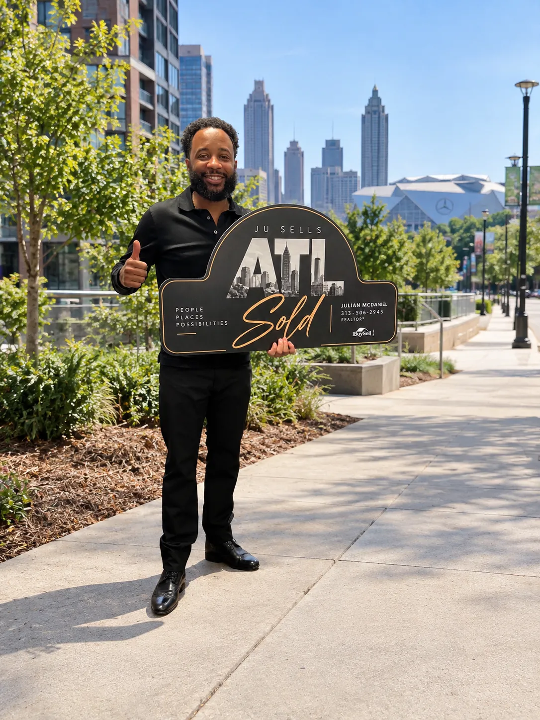 Julian standing beside a Ju Sells ATL sold sign on a South Downtown sidewalk