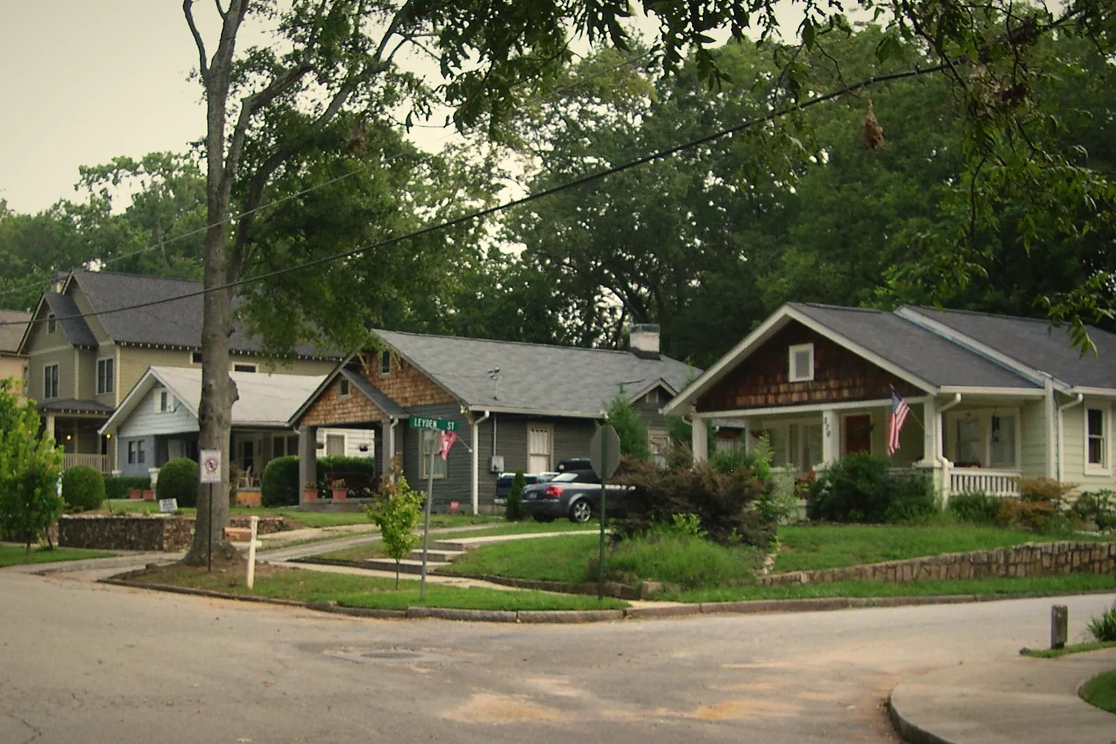 A row of older bungalows with front porches on a tree-lined street in Oakhurst, Decatur