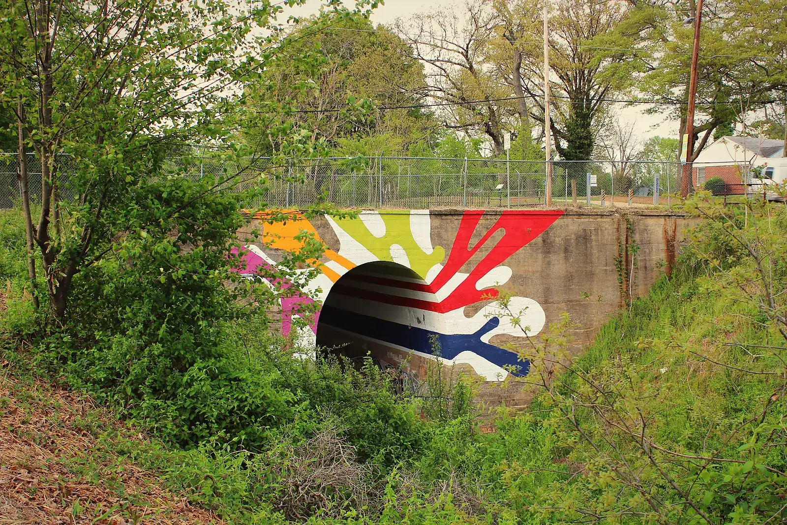 A colorful mural on the Lucile Avenue bridge over the BeltLine Westside Trail, framed by spring trees