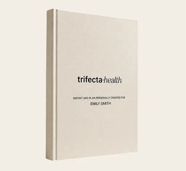 Beige hardcover book titled "trifecta health" with text below saying "Report and plan personally created for Emily Smith."
