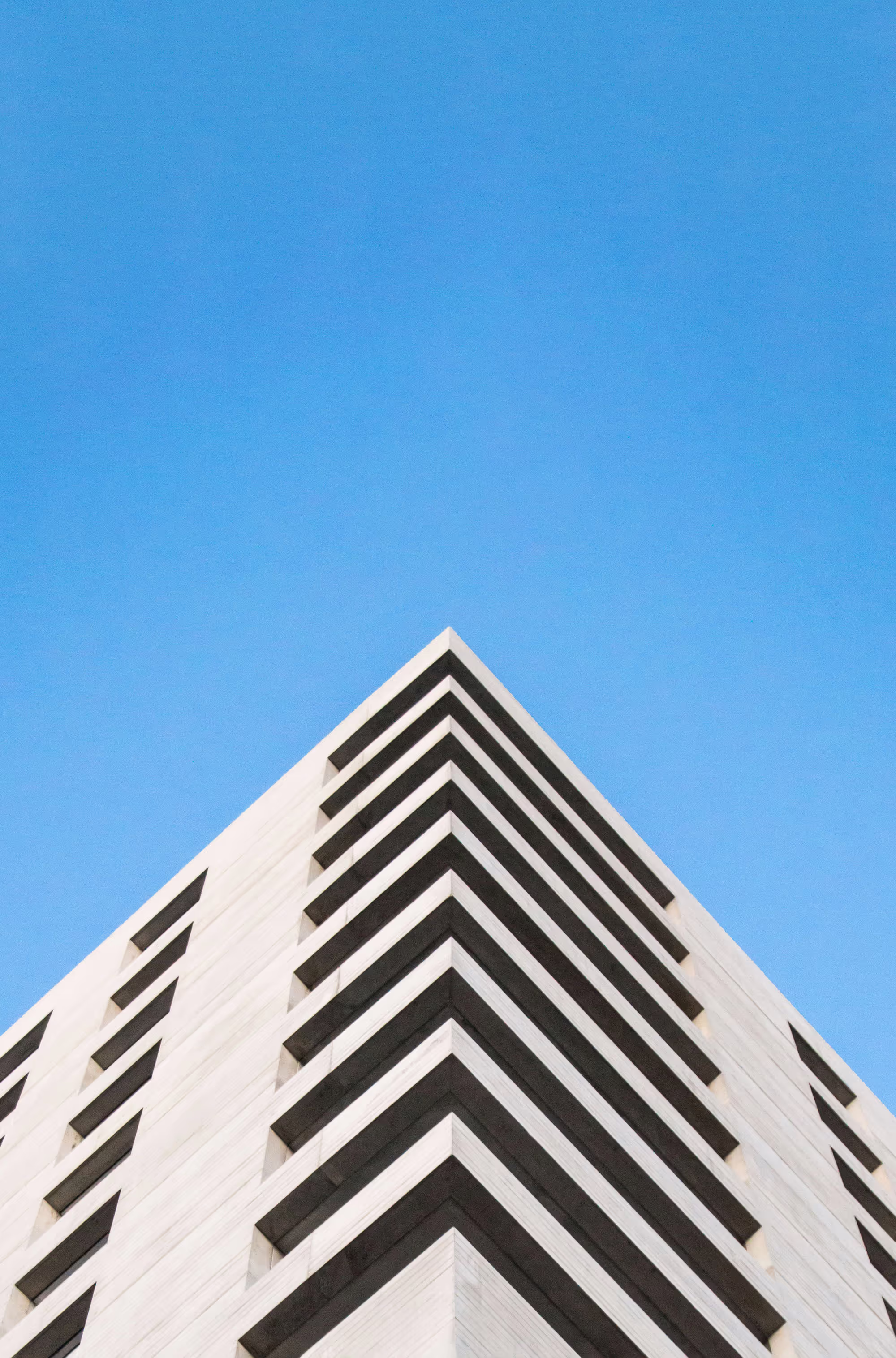 Modern building towering against a clear blue sky, with sleek lines
