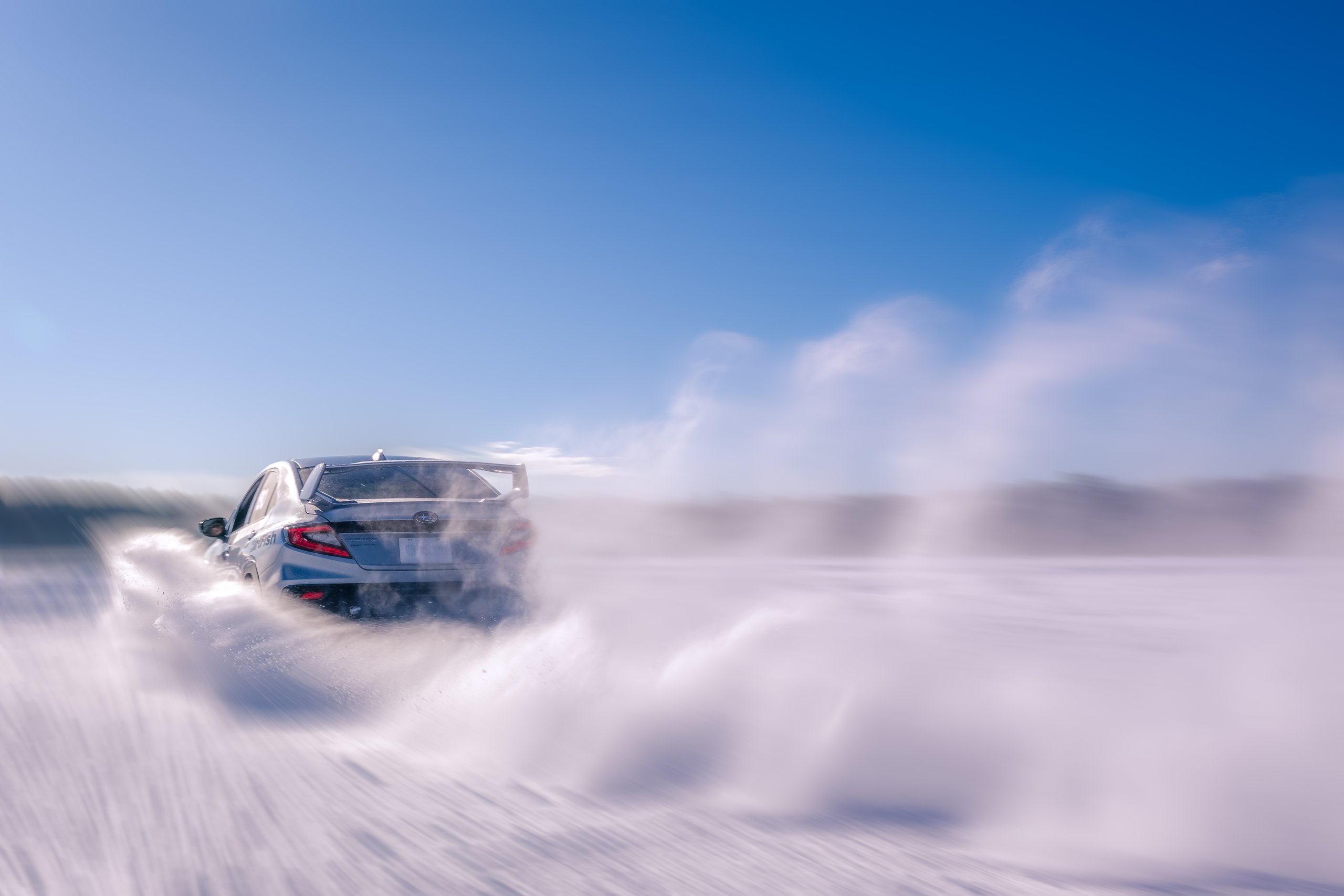 Subaru drifting at speed on the frozen Dollar Lake during an advanced Ice Driving USA program
