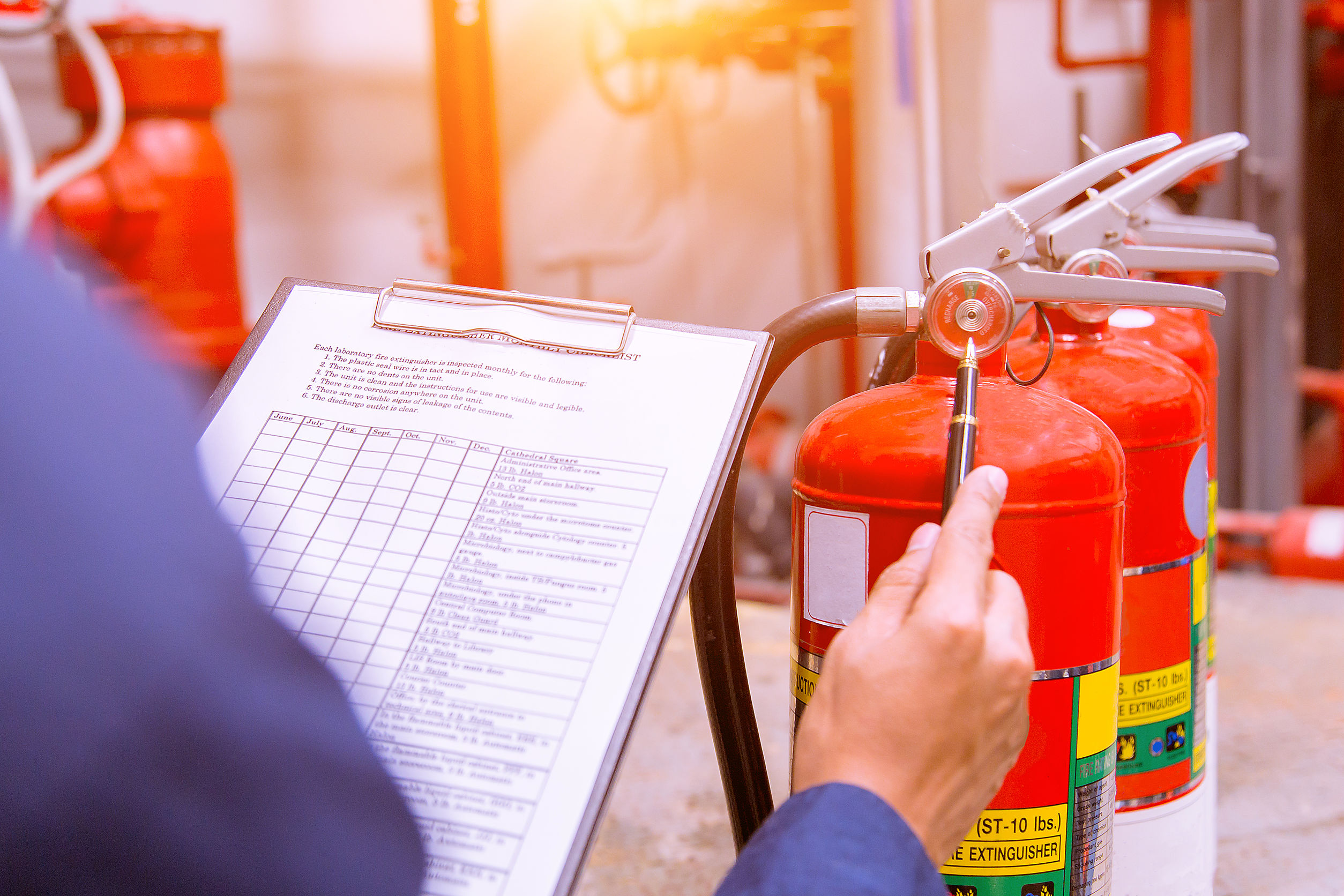 Engineer inspecting fire extinguishers with a service checklist