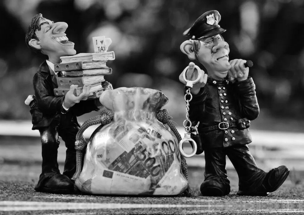 Figurines of a man carrying stacks of money beside a police officer holding handcuffs