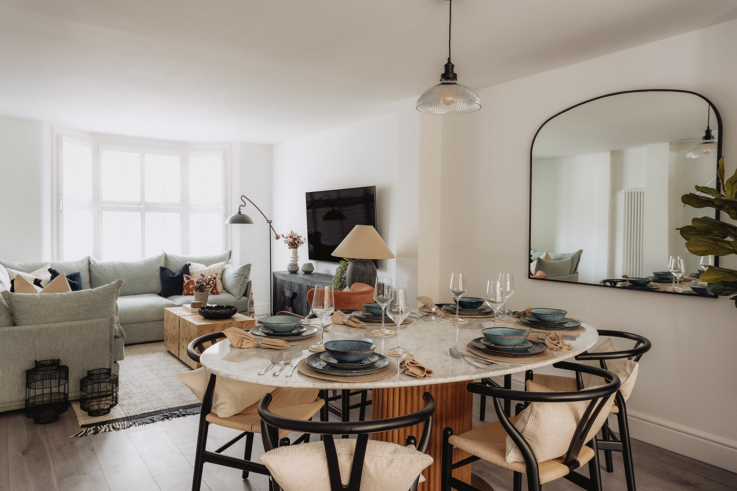 Dining room with a round marble table, pendant light and arched mirror