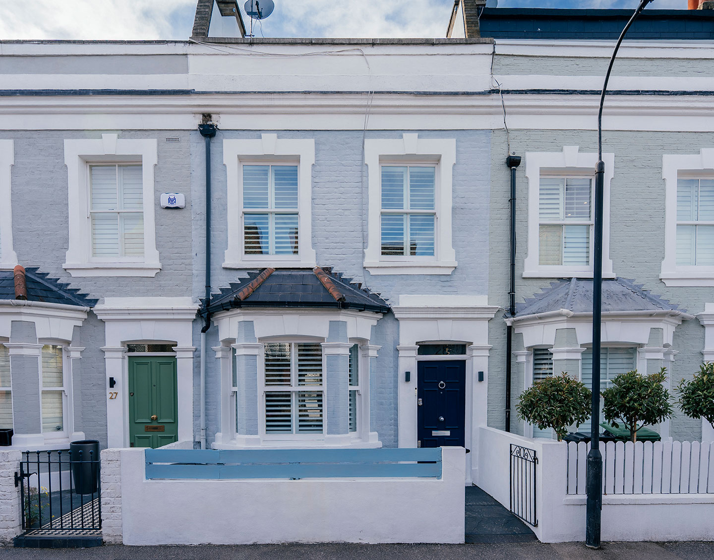 Pale painted Victorian terraced houses with white bay windows on a South West London street