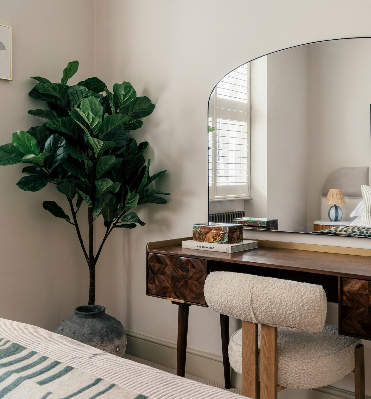 Bedroom dressing table with an arched mirror and a fiddle-leaf fig plant
