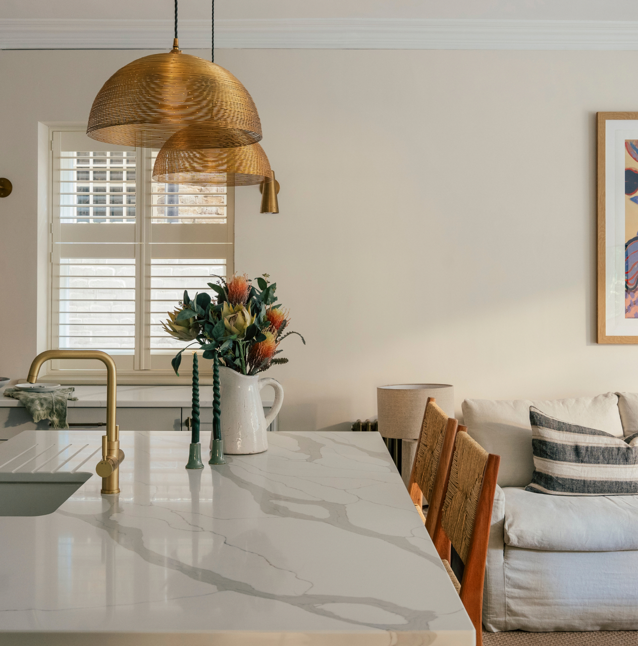 Kitchen island with brass pendant lights opening onto a living area