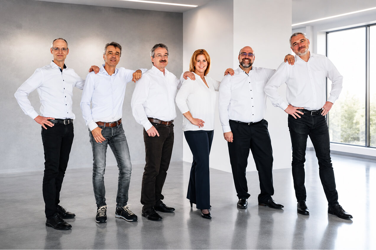 Group of WALTEC executives standing in a row in a bright room, all wearing white shirts and smiling with relaxed postures.