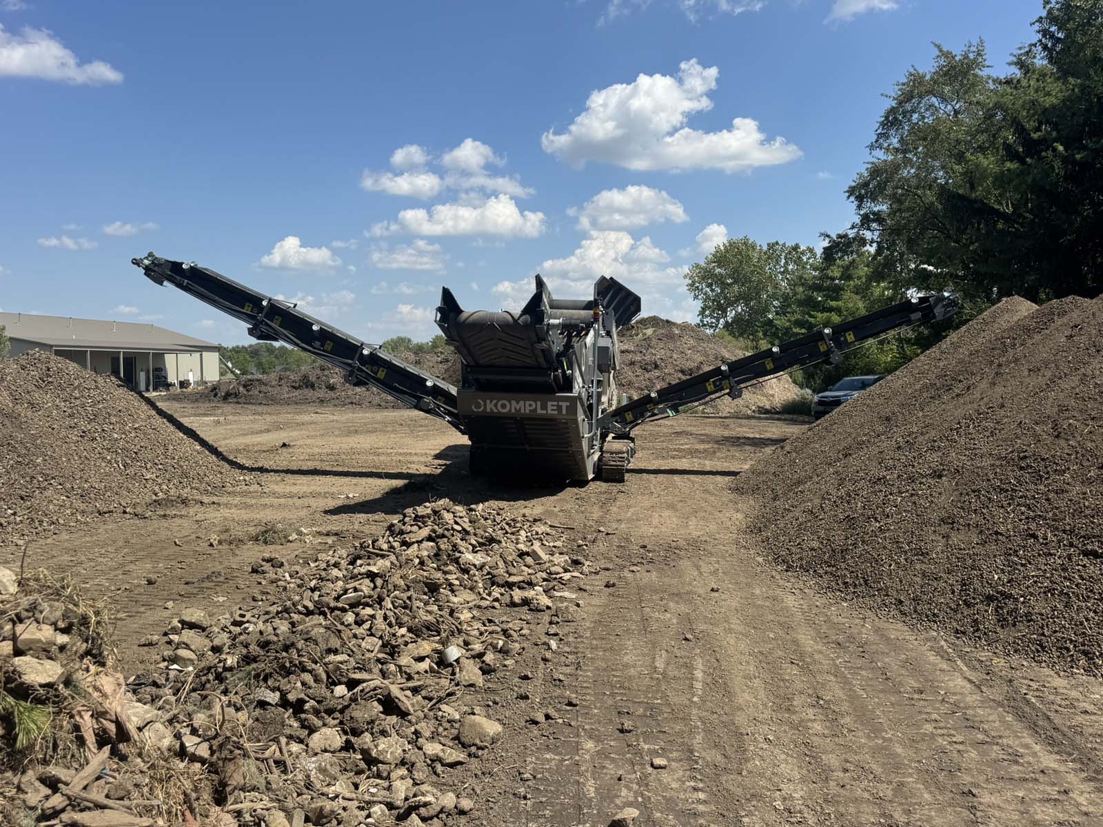 Komplet mobile screener set up between screened soil piles