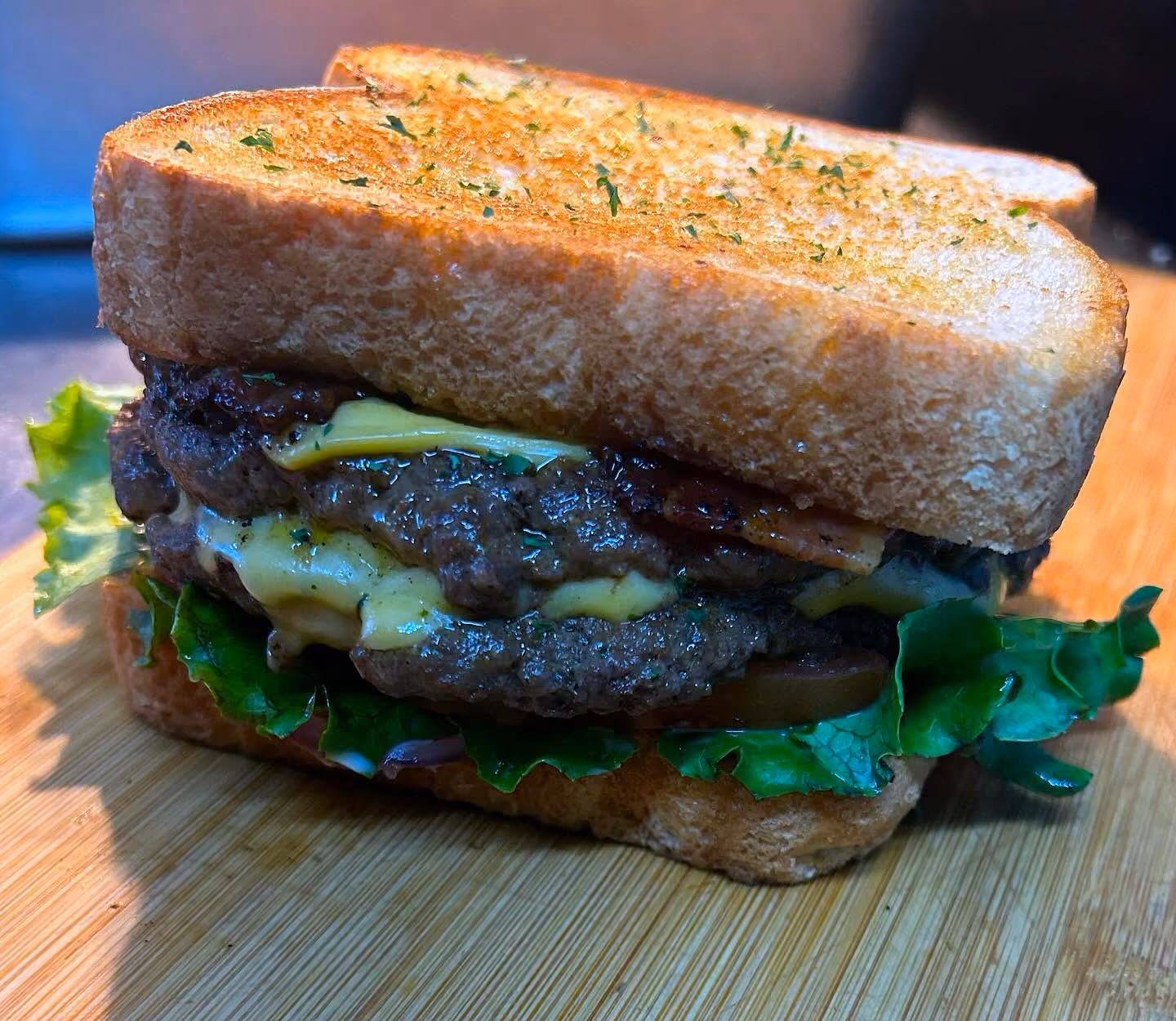 A sandwich with lettuce, tomato, and bacon on a wooden cutting board.