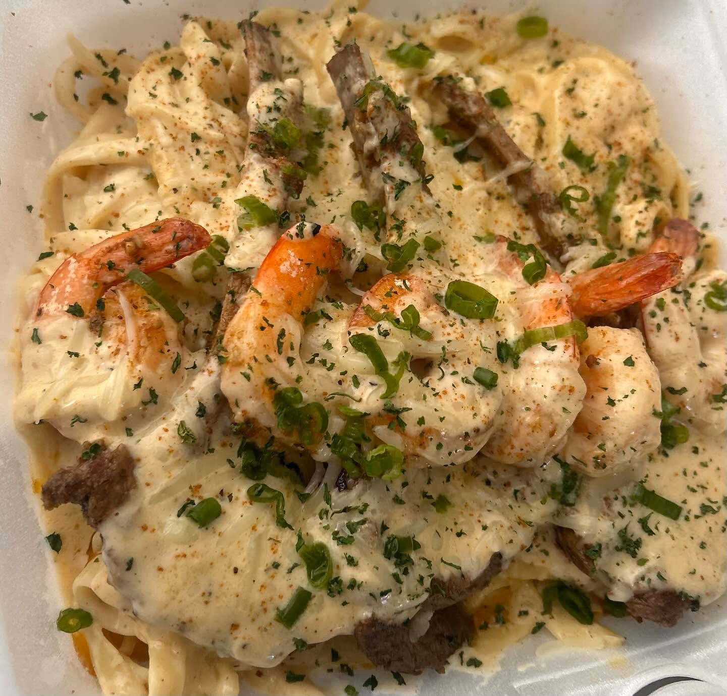 A white bowl filled with shrimp and pasta.
