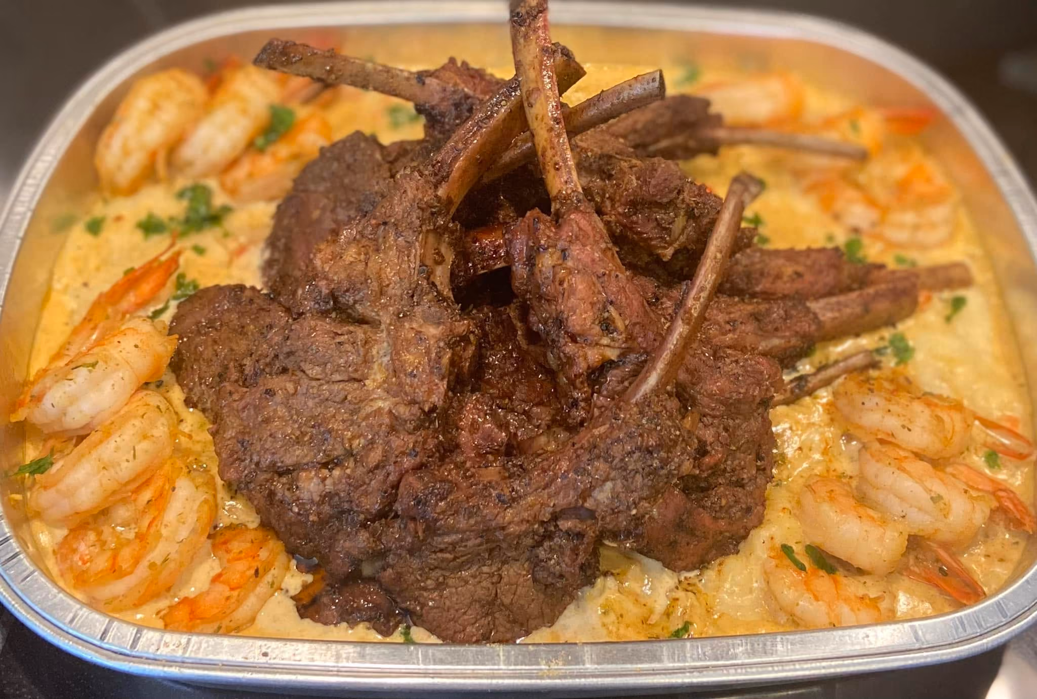A close up of a meal with shrimp, meat, and vegetables.