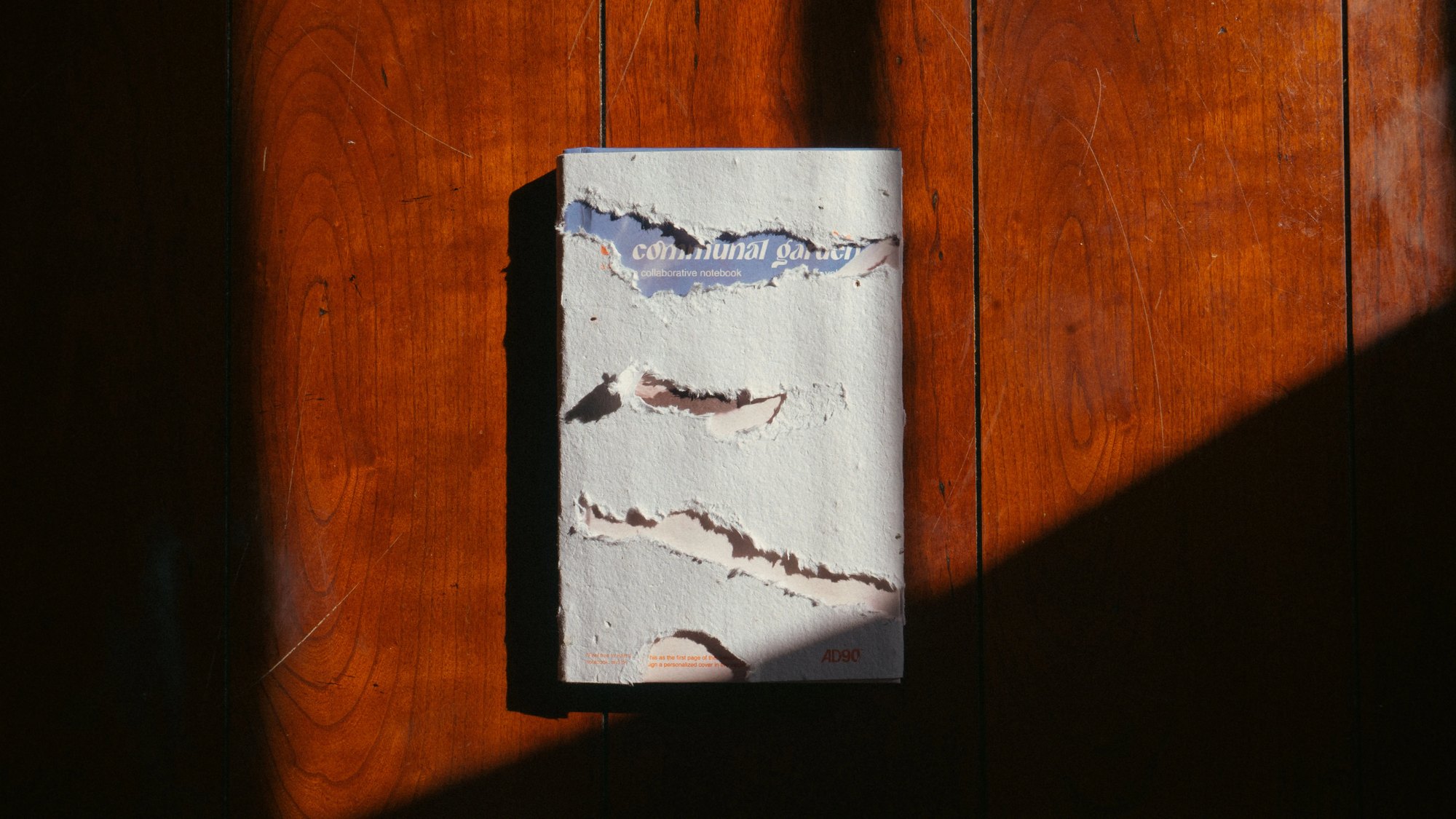 Communal Garden hardcover in its torn seed paper dust jacket on a sunlit wooden table
