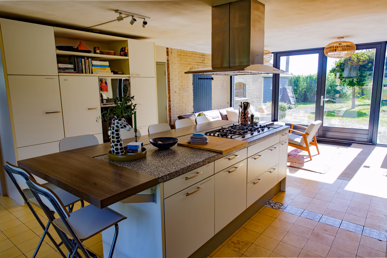 Guest area kitchen island with gas hob and wooden bar counter, glass doors opening onto the garden