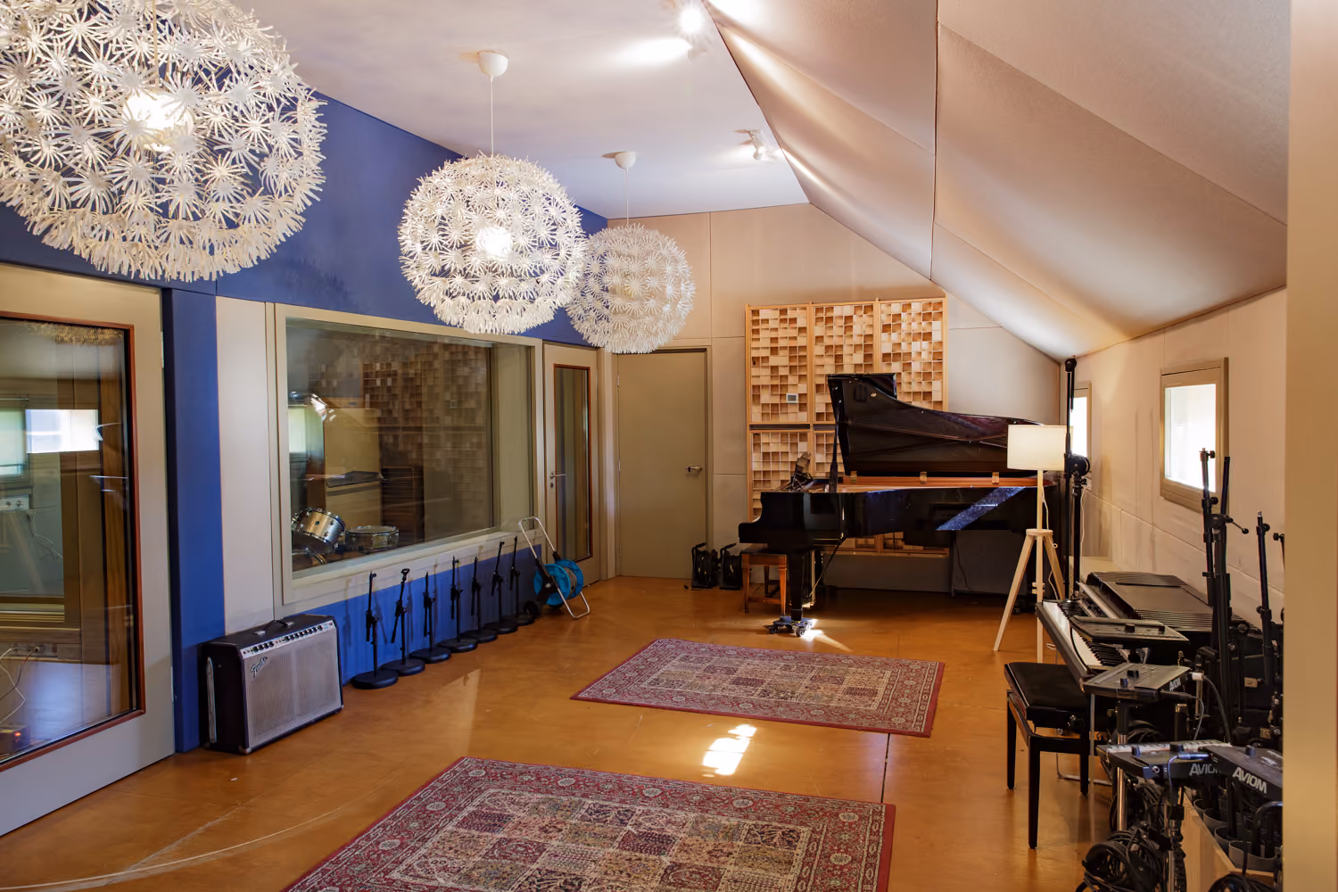 Studio 1 live room with dandelion pendant lights, blue walls, Persian rugs, a grand piano and a Fender amp