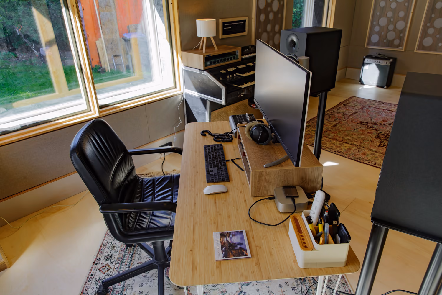 Studio 2 production desk with monitor, headphones and Mac mini by a large garden window, vintage organ behind