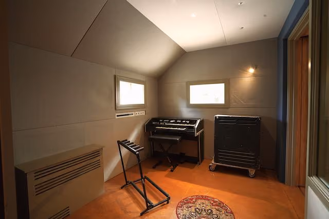 Booth 3 in Studio 1 with a vintage organ and stool, a speaker cabinet on wheels and a guitar stand