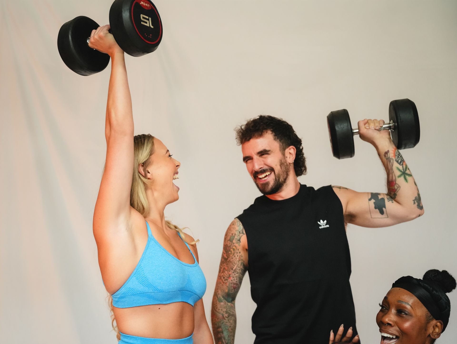 Smiling man and woman each lifting a dumbbell overhead