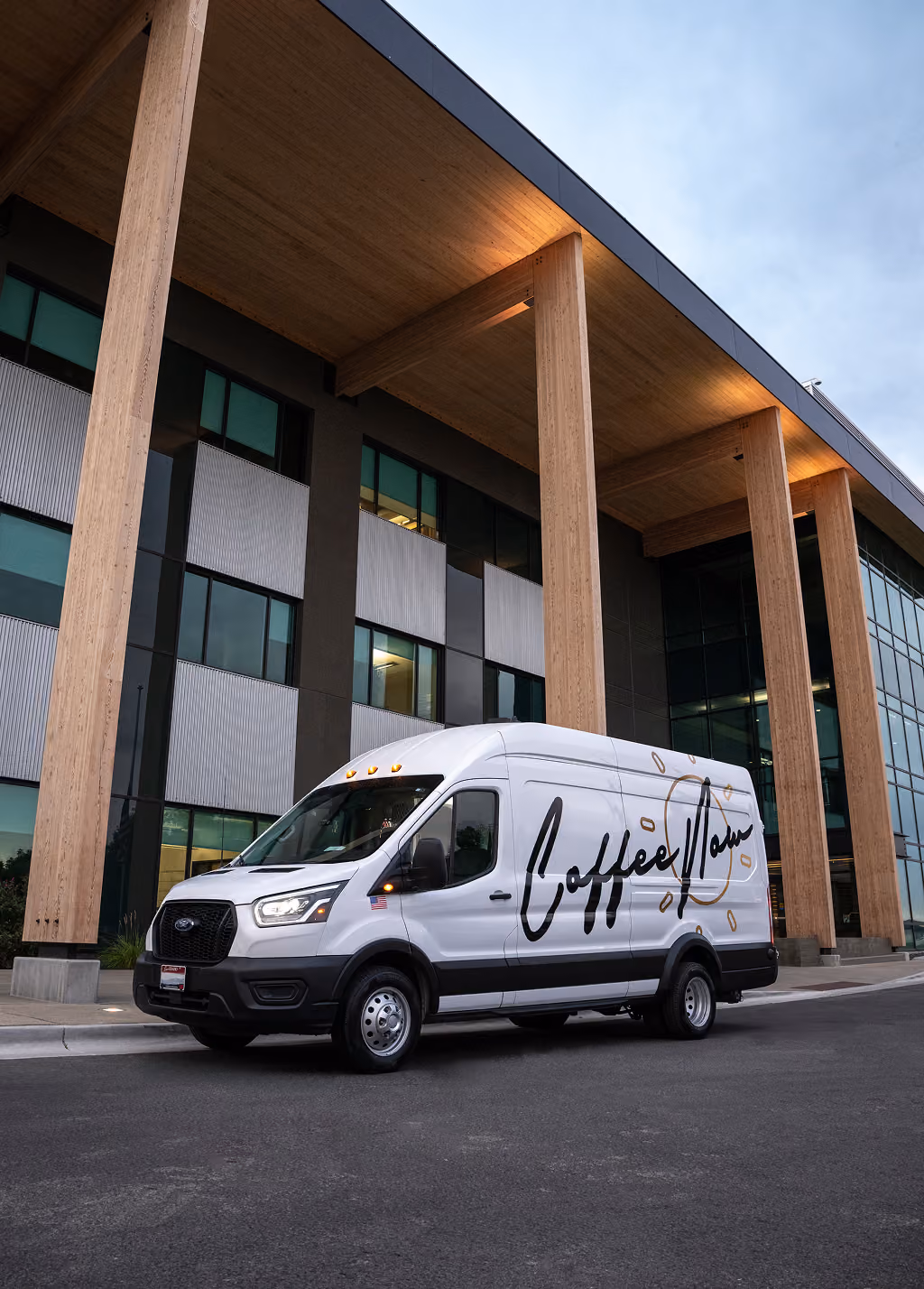 CoffeeNow van parked in front of a corporate building.