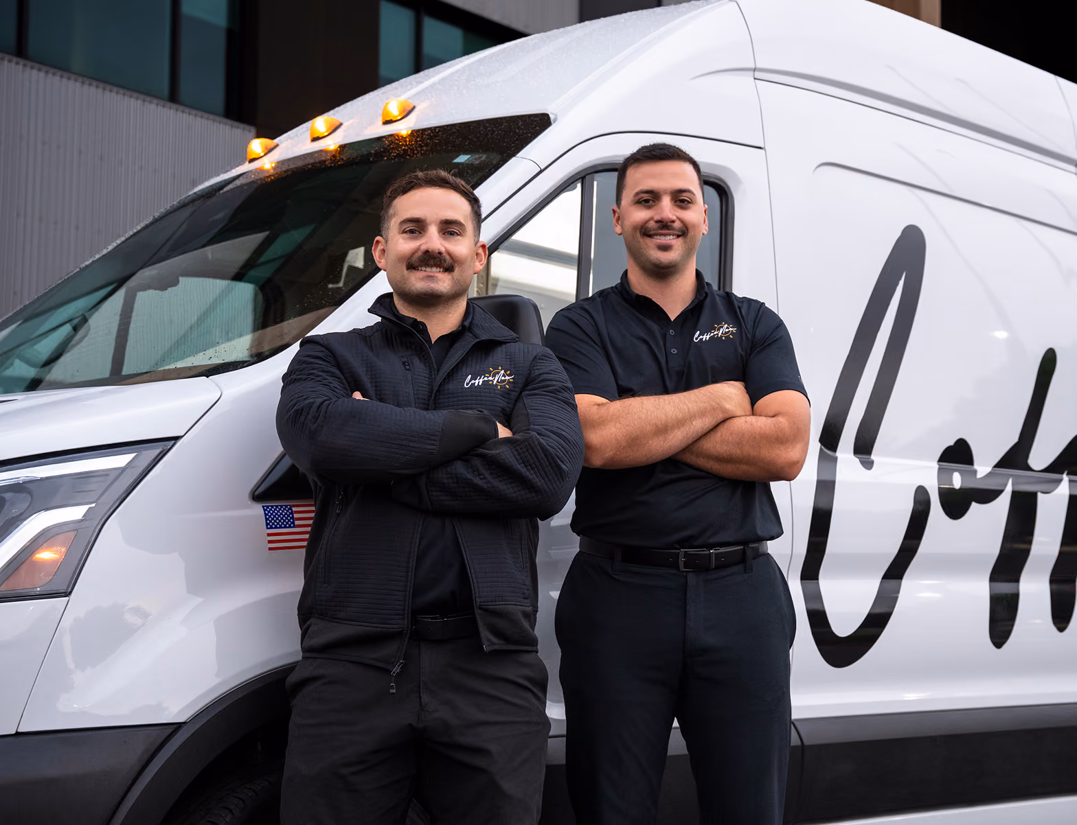Founders Jordan West and Kaleb Schrank standing with arms crossed in front of a CoffeeNow van