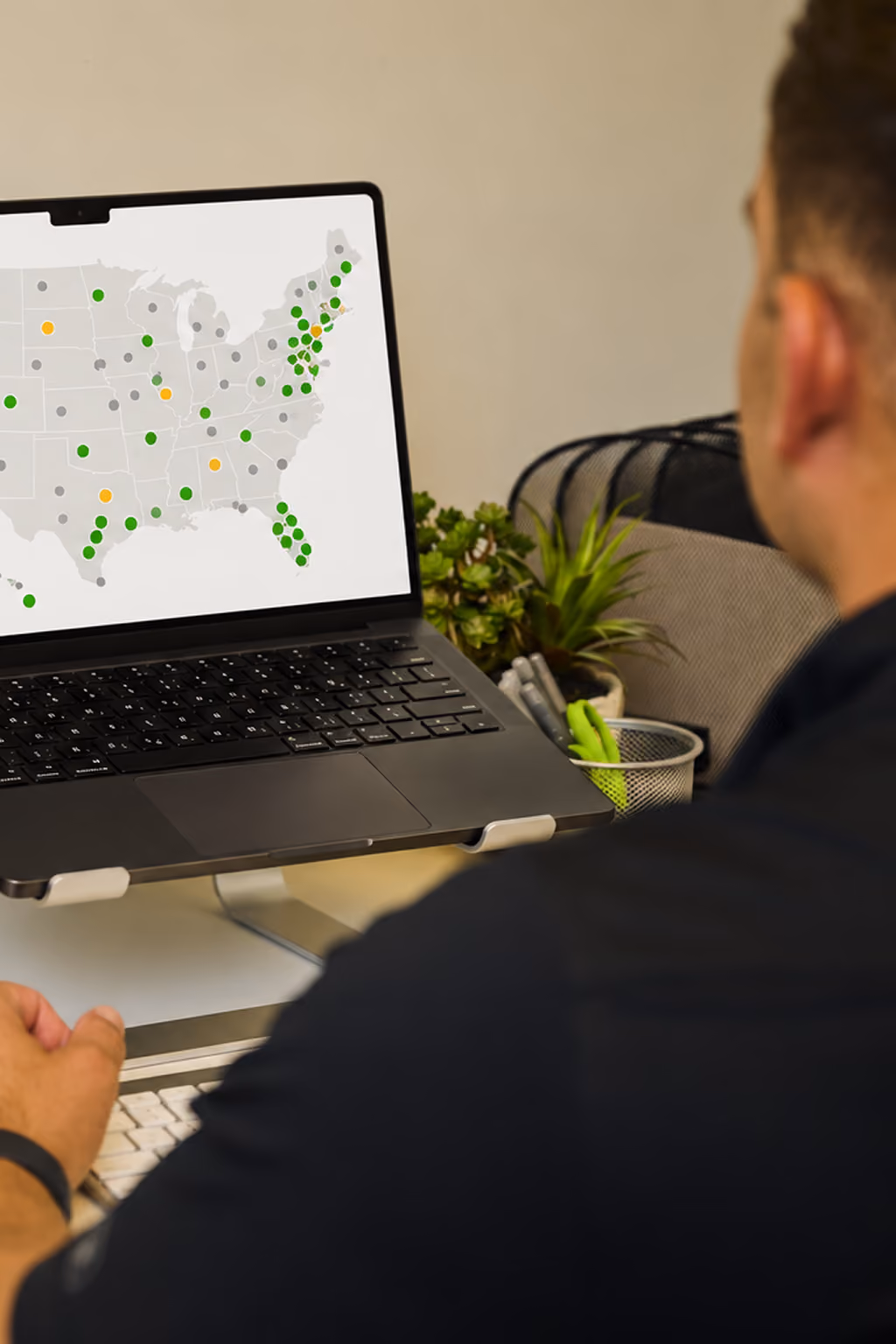 Person viewing a laptop screen with a map of the United States showing colored dots at various available CoffeeNow territories.