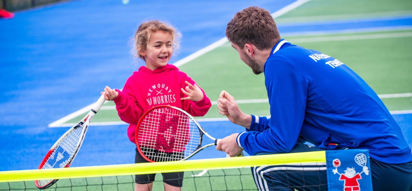 A coach high-fiving a young player across the net
