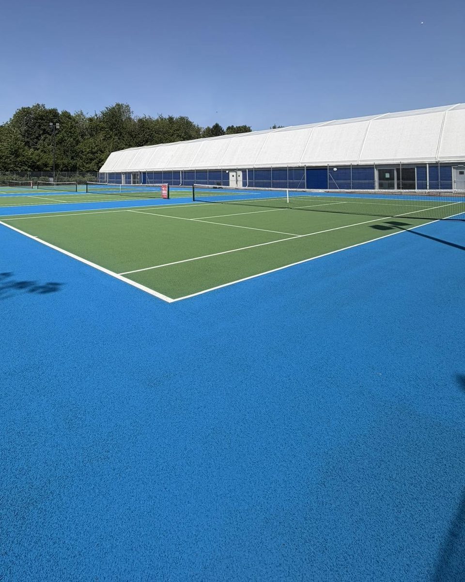 Resurfaced outdoor courts with the indoor tennis hall behind at War Memorial Park