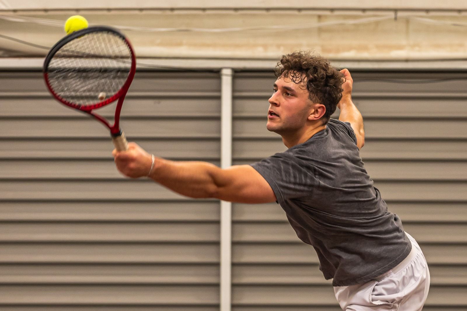 Player stretching for a backhand volley on the indoor courts at War Memorial Park